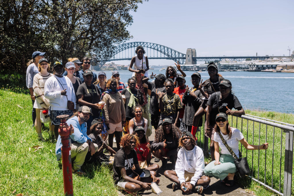 Students from Milingimbi School and Pymble Ladies' College pose for a photo in front of the Sydney Harbour Bridge.